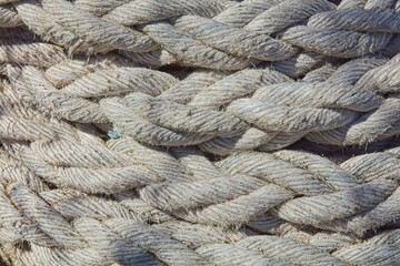 Closeup of tangled pile of old thick ship rope faded in color from use and weather.