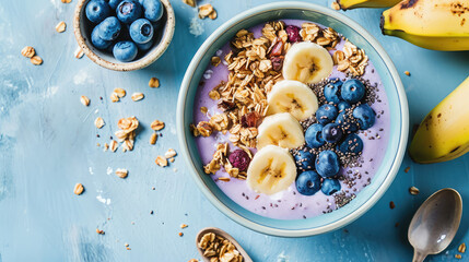 Сlose-up of a healthy vegan breakfast. A plate with healthy superfood - fresh berries, fruit yogurt, chia seeds, granola and banana slices on pastel table.  - obrazy, fototapety, plakaty