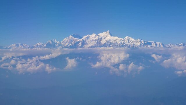 Hovering in the blue sky watching the mountain range shining like diamond with sunshine, an aerial shot of mountains and cloud from airplane