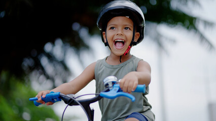 Portrait little cute adorable mixed race toddler boy in safety helmet enjoy having fun riding...