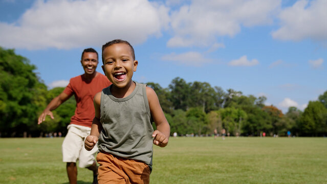 Father and son playing catch-up game outdoors running after each other through city park. Families. Fun, entertainment.

