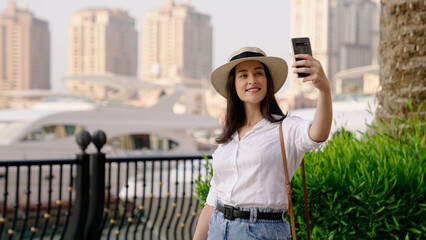 tourist woman taking selfies at Porto Arabia promenade at The Pearl island at Doha Qatar
