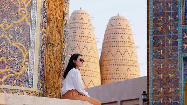 tourist woman sitted at Blue mosque of Katara village made of colorful mosaic in Doha Qatar showing Pigeon tower behind
