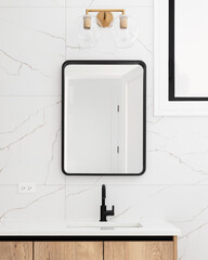 A bathroom detail with a wood cabinet, marble tiled wall, and gold light fixture above a black...