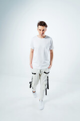 a photo shoot of a Russian guy on a white background. A Russian model poses in a fashionable summer T-shirt. photo shoot of youth clothes with a model in a photo studio