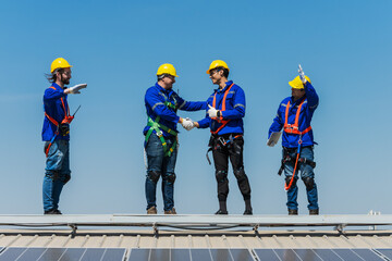 Group of solar engineers shaking hands after finish solar panels installation on factory roof