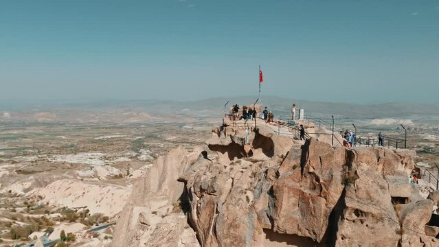 Aerial drone footage of ancient cave town Uchisar in Cappadocia Turkey . Landscape of a city built around huge limestone castle with fairy chimneys on mountain background.