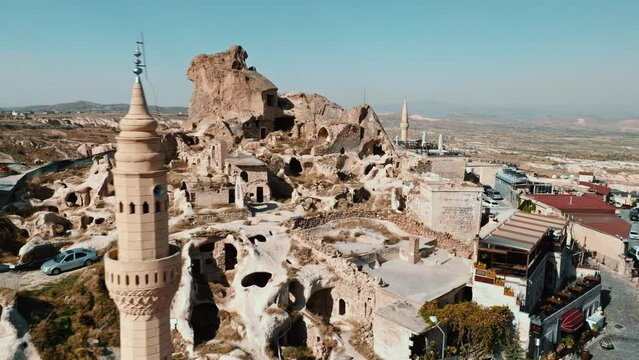 Aerial drone footage of ancient cave town Uchisar in Cappadocia Turkey . Landscape of a city built around huge limestone castle with fairy chimneys on mountain background.
