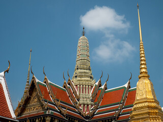Fototapeta premium El techo ornamentado y hermoso de varios niveles de un templo budista tradicional tailandés o wat con chedis dorados se destaca contra un cielo azul claro en Bangkok, Tailandia.