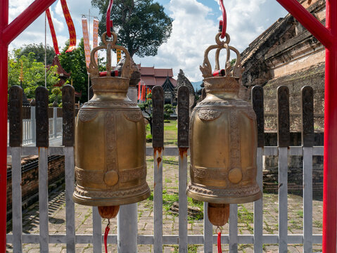 Dos grandes campanas de oraci&oacute;n de bronce adornadas cuelgan en el patio de un templo budista tradicional en Tailandia, invitando a los visitantes a tocarlas para obtener buena suerte y bendiciones.