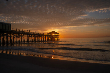 Fototapeta premium Sun rising behind the hut on the end of the pier