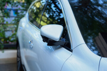 Rear-view mirror closed for safety at car park,  Side mirror of white car , black tinted glass