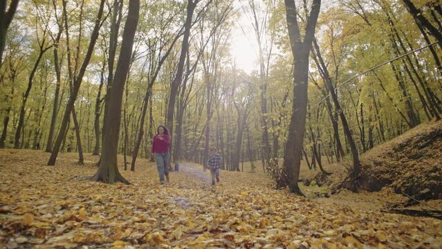 Basking in Autumn's Glow: Mother and Son Share Laughter, Throwing Leaves in the Park. High quality 4k footage