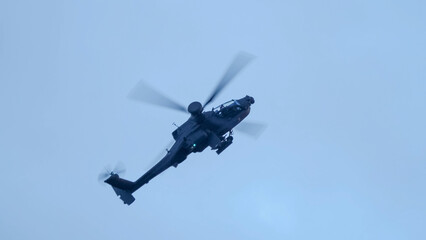 close-up of a British army Boeing Apache Attack helicopter gunship AH64E (AH-64E ArmyAir606) at full bank in a hammerhead stall turn, Wiltshire UK