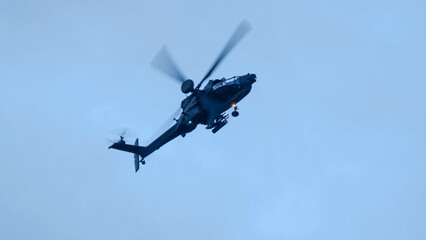 close-up of a British army Boeing Apache Attack helicopter gunship AH64E (AH-64E ArmyAir606) at full bank in a hammerhead stall turn, Wiltshire UK