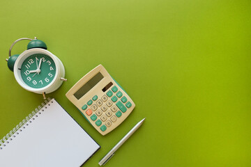 Composition with a classic alarm clock, calculator, clean spiral note on green background, top view - obrazy, fototapety, plakaty
