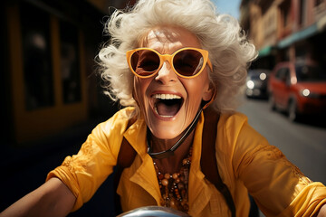 happy aged woman in yellow clothes driving a motorcycle - 700690450