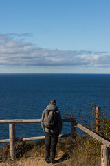 Back view of a man with backpack  looking out on the sea.