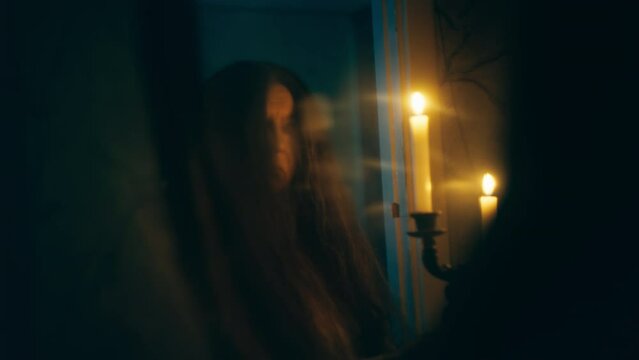 Possessed old woman with burning candles looking in mirror, doing black magic