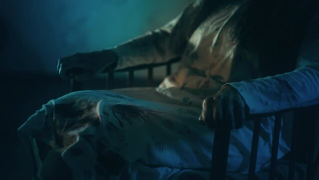 Close-up of woman in bloody nightgown sitting in armchair at haunted castle room