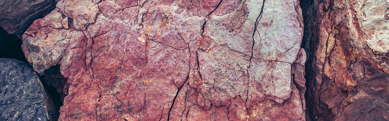 The surface of the mountain stone wall photo. Rock texture. Pink grunge background near seaside.