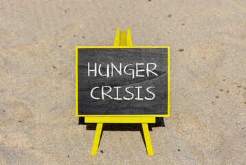 Hunger crisis symbol. Concept words Hunger crisis on beautiful black chalk blackboard on a beautiful beach sand background. Business, support and Hunger crisis concept. Copy space.