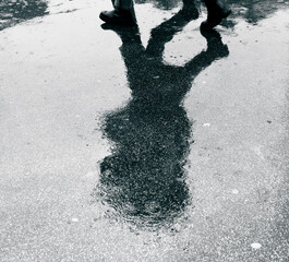 Fototapeta premium silhouette of a person with umbrella on a wet asphalt