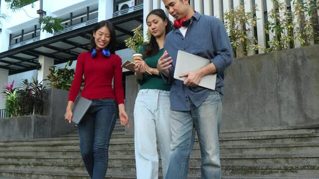 Happy young asian students chatting with each other after class standing outside. Guy and girls wear casual clothes to study. Lifestyle concept.