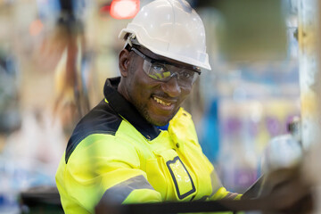 Close-up photo of a smiling African male engineer working in a plastic and steel industry. Wear a...