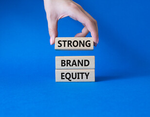 Strong Brand Equity symbol. Concept words Strong Brand Equity on wooden blocks. Businessman hand. Beautiful blue background. Business and Strong Brand Equity concept. Copy space