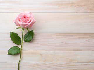 A single pink rose sitting on top of a wooden floor