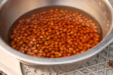 Brown Chickpea or channa soaked in water in a steel vessel or bartan, steel utensil