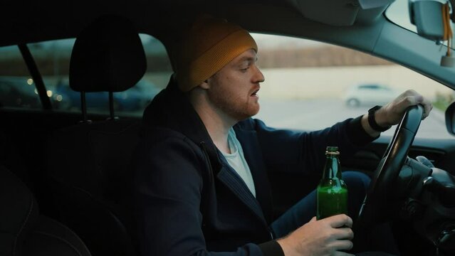 Serious man driver with beer bottle in hand driving car