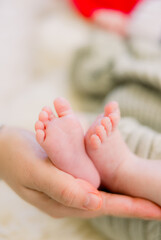 Obraz na płótnie Canvas A close-up of sweet newborn foot and toes with a parent holding the feet
