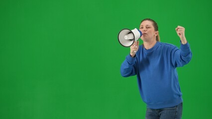 Female activist with raised fist shouting into megaphone in studio on green screen. Front view of a...