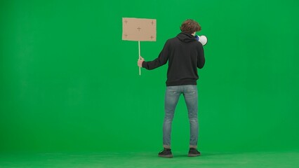 Man facing away from camera speaking into a megaphone and holds a blank placard in her hand. Back...