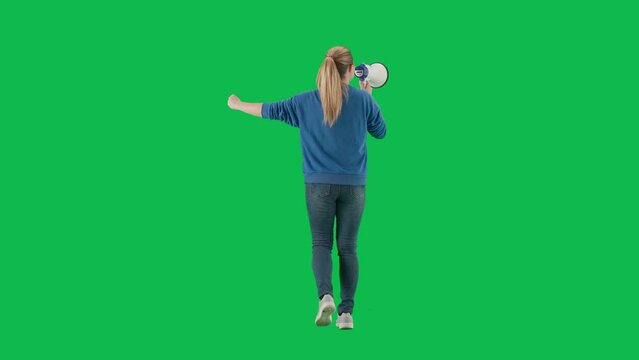 Woman facing away from camera speaking into megaphone with raised fist. Back view of a woman walking with a mouthpiece on a green screen. Protest action, fight for women's rights, strike.