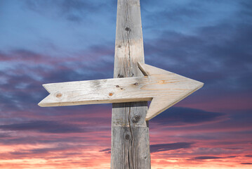 Wooden arrow on a post, with sunset sky in the background