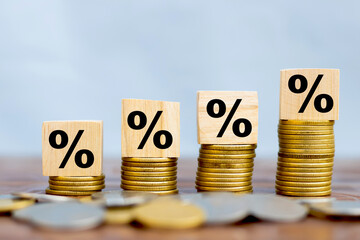 Wealth growth concept percentage icon print on wooden cube placed on stack of coins