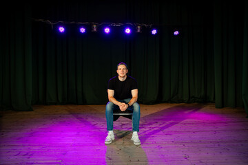 aspiring actor sitting center stage under spotlights, contemplating his next performance in an empty theater