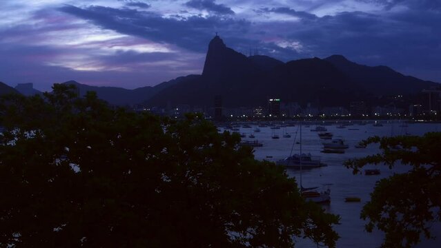 High perspective timelapse of Botafogo Bay in Rio de Janeiro, Brazil at sunset with iconic Christ the Redeemer Statue visible - UNESCO World Heritage Site