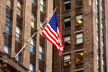 The beautiful big American flag flying on the skyscraper buildings of the Manhattan district in the Big Apple, symbol of New York City.