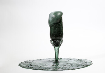 A glass with a foamy black cocktail on a white background, foam in a glass