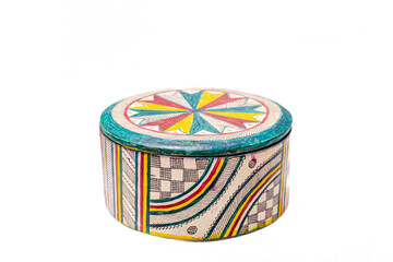 A circular box closed with its lid. With lots of patterns and colors. A checkerboard, curves,...