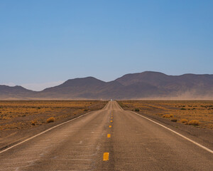 Fototapeta na wymiar a lonely road (state road 375) in southwestern USA, in Nevada near area 51, dry arid desert landscape and bright light.