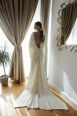 beautiful bride in elegant wedding dress and accessories posing in elegant hotel room