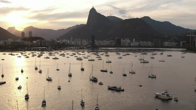 Aerial drone approaching Botafogo Bay in Rio de Janeiro, Brazil at sunset with iconic Christ the Redeemer Statue visible - UNESCO World Heritage Site