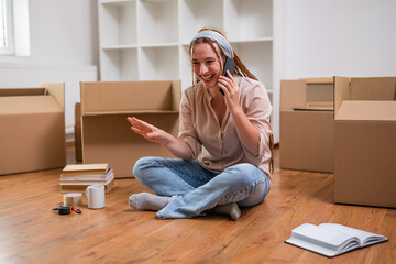 Modern ginger woman with braids talking on the phone while moving into her new apartment.	