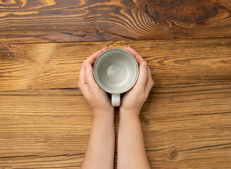 Hand Holds Cup, Empty Cup in Hands, Coffee Mug, Teacup Mockup, Cup in Arms on Wooden Table