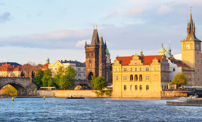 Fototapeta premium View of old town with Charles Bridge (Karluv Most) on Vltava river and Old Town Bridge Tower, famous tourist destination in Prague, Czech Republic (Czechia), at sunset